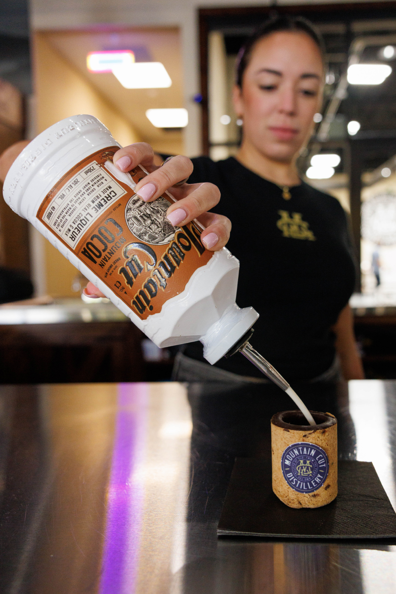A woman pouring liquer into a shot glass shaped cookie